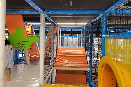 Children climbing on a colorful indoor climbing wall in an indoor playground.