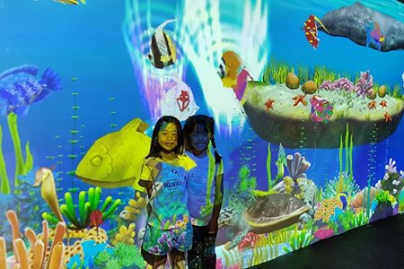 Children interacting with VR projection games in an indoor playground.