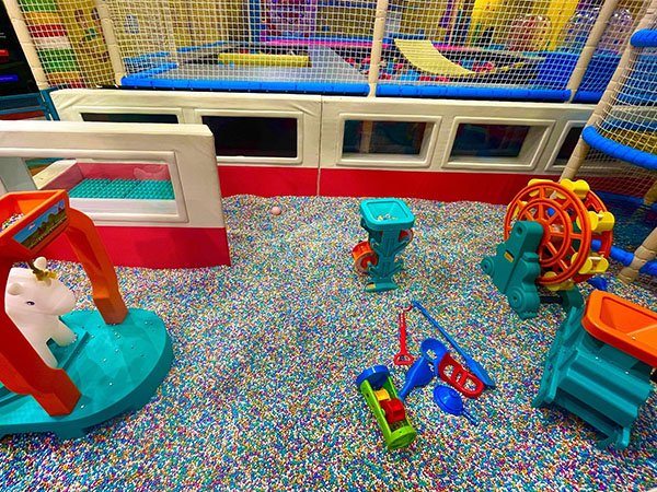 Children playing with colored sand in a themed indoor sand play zone