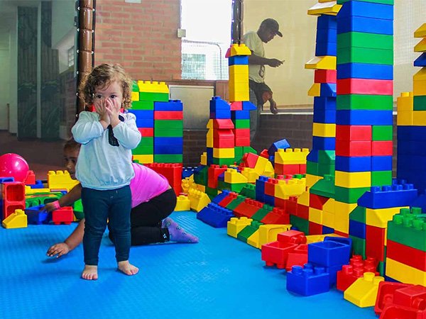 Children playing in an indoor building block area with colorful soft play equipment